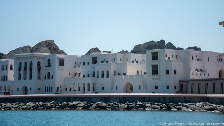 White waterfront buildings beneath rocky mountains.