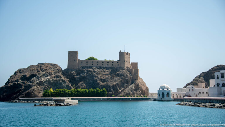 Fort and towers on low rocky island or headland.