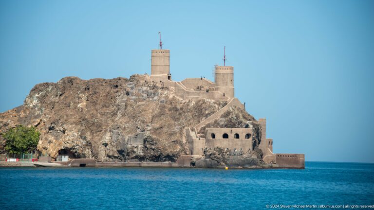 Fortified rocky headland with round towers.