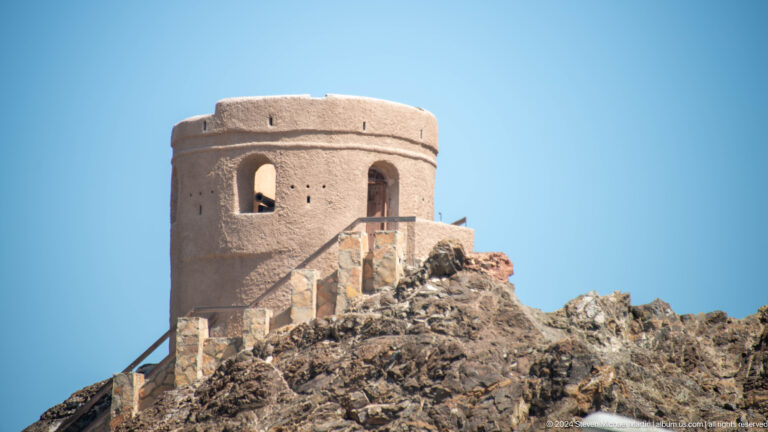 Round stone watchtower on rocky ridge.