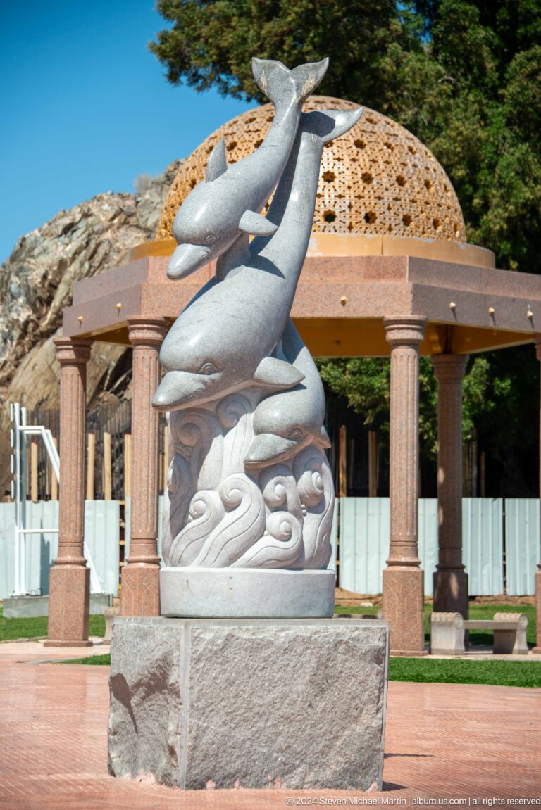 Silver fish sculpture beside pavilion columns.