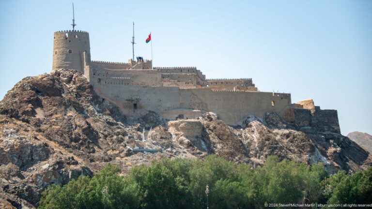 Fort wall and flag on rocky slope.