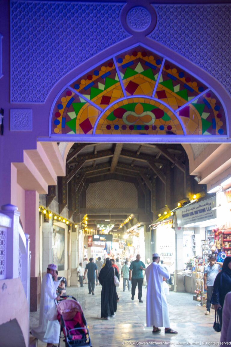 Covered market corridor under colorful arched sign.