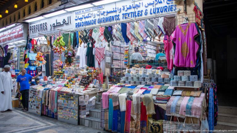 Textile stall with shirts scarves and hanging garments.