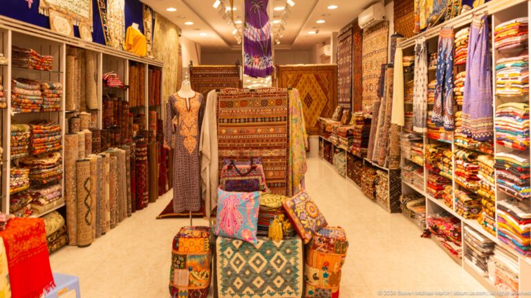 Carpet shop with stacked and hanging rugs.