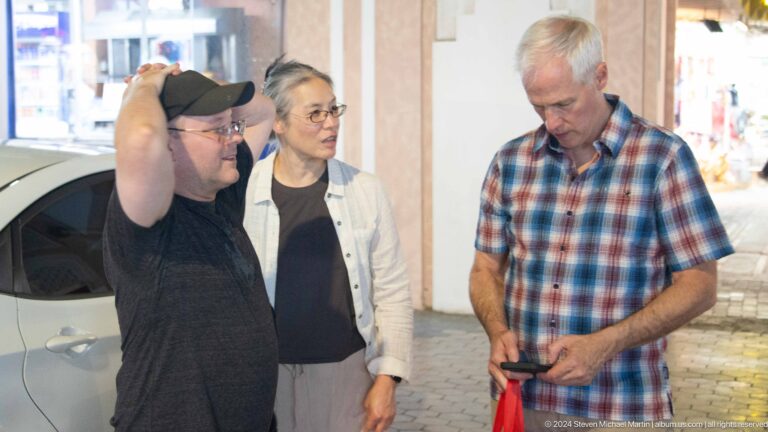 Three visitors standing indoors during market visit.