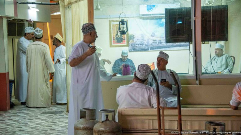 Barbershop interior with seated customer and attendants.