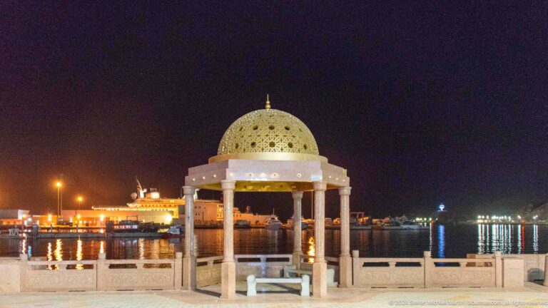Domed waterfront pavilion lit at night.