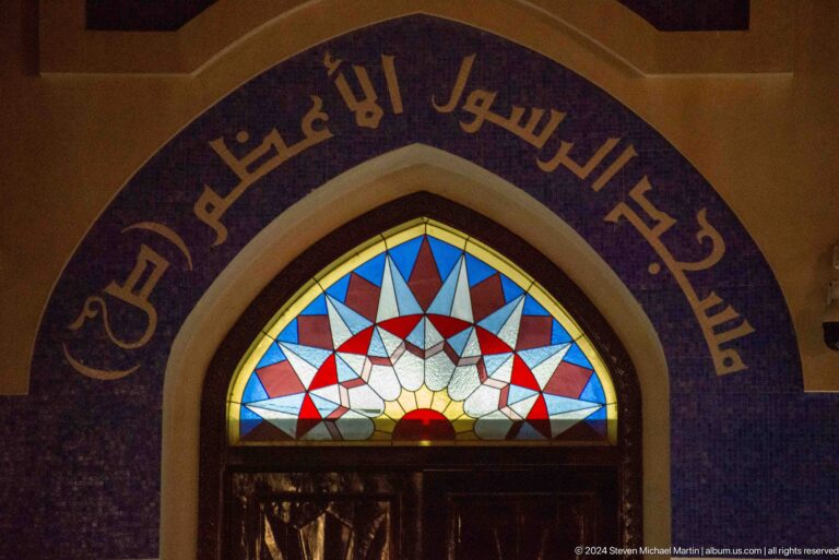 Arched entrance with arabic inscription and stained glass.