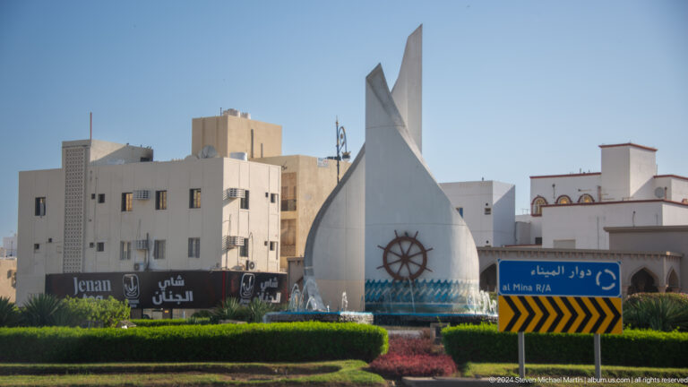 White sail-shaped roadside monument in daylight.