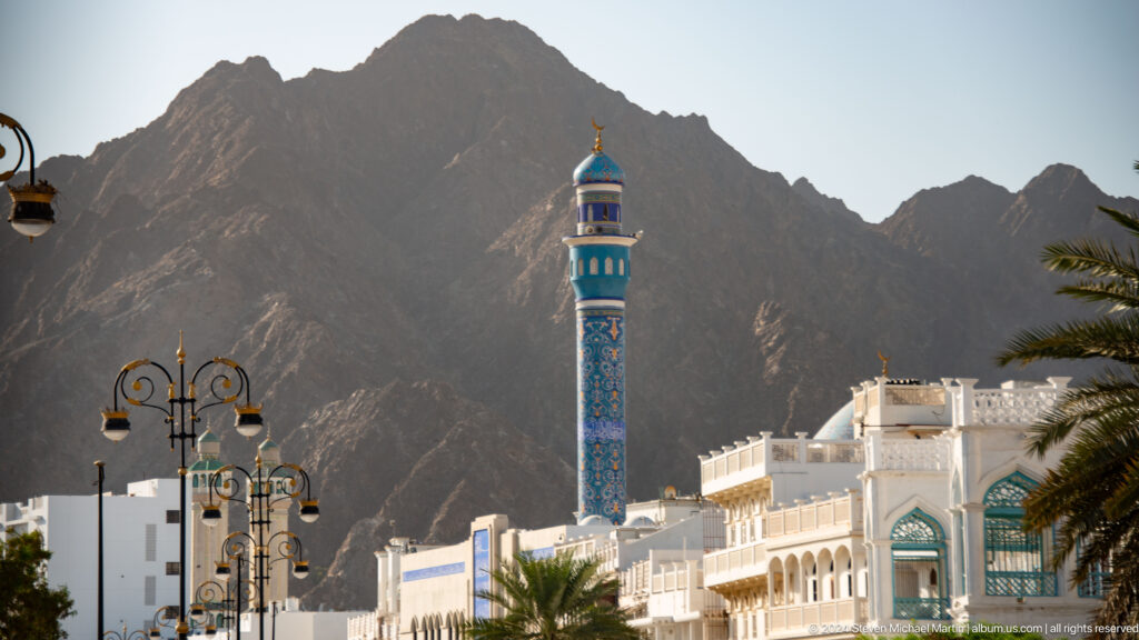 Blue-tiled minaret rising before dark mountains.