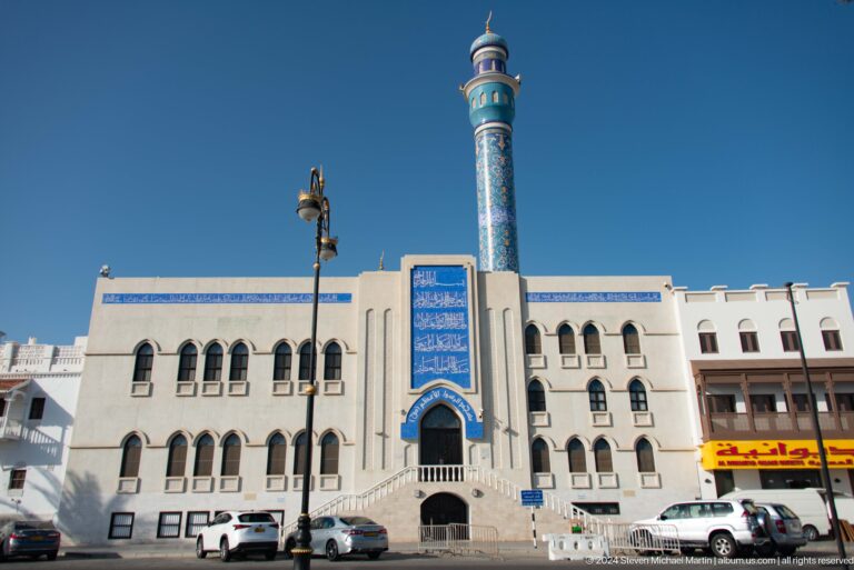 White mosque façade with blue minaret.