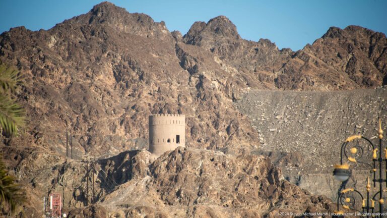 Isolated round watchtower on rocky hillside.
