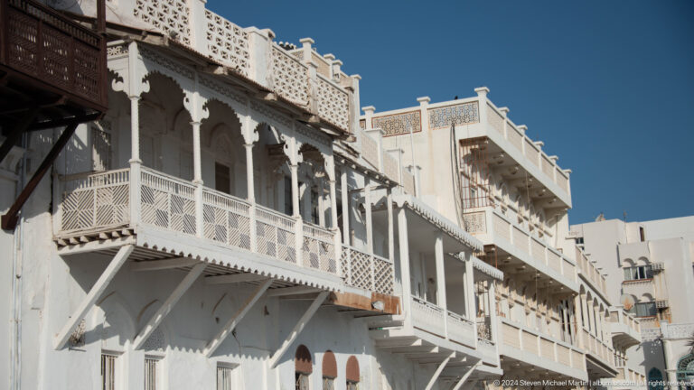 White traditional building with carved wooden balconies.