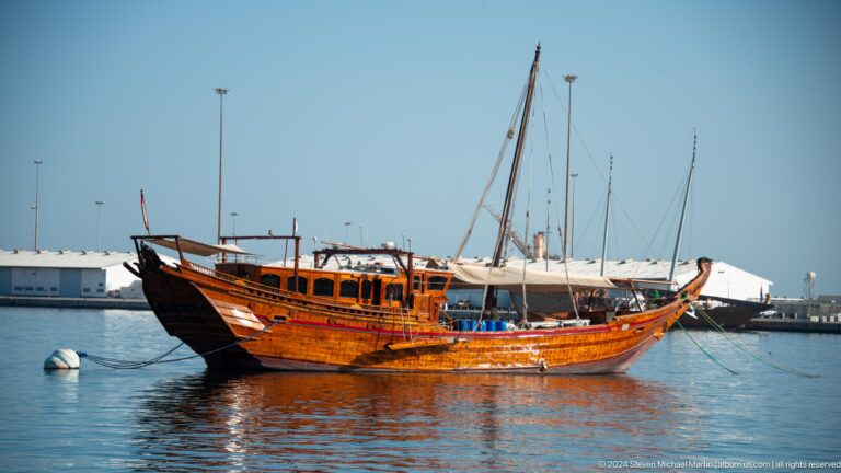 Large wooden dhow with long bowsprit.