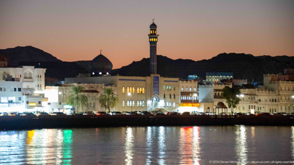 Waterfront mosque and minaret reflected in harbor at dusk.
