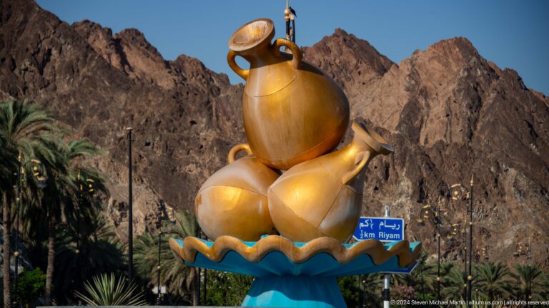 Large gold incense burner sculpture by mountains.