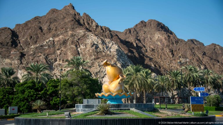 Gold incense burner sculpture in landscaped setting.