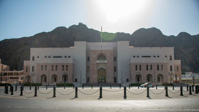 Symmetrical white institutional building with central arch.