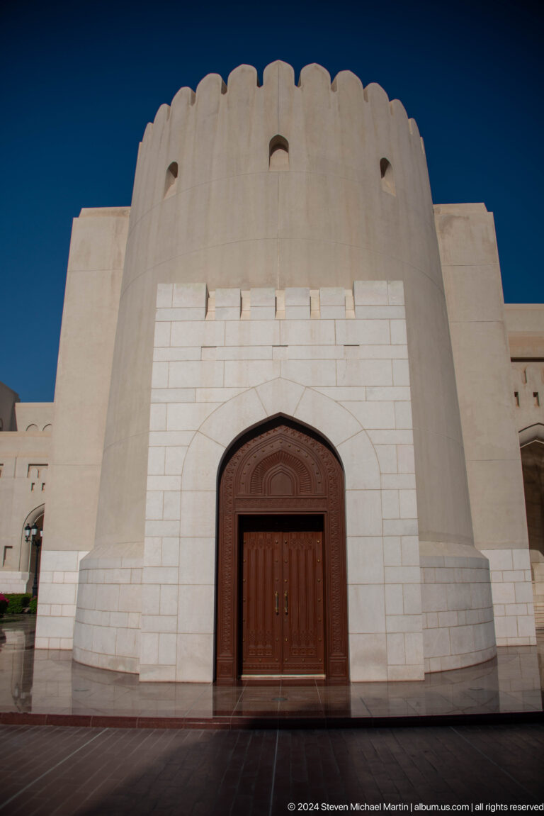 Close view of pointed wooden doorway in pale wall.