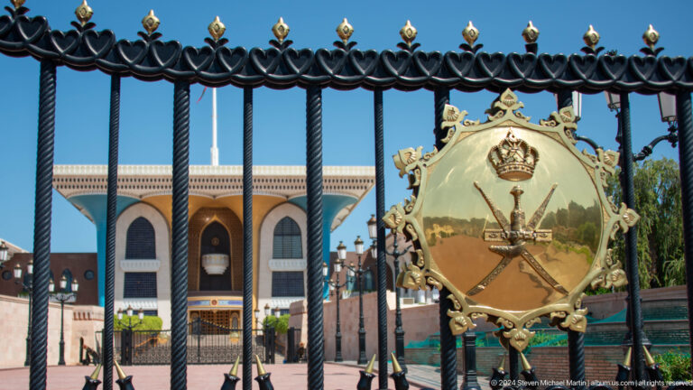 National emblem framed by black iron fence.