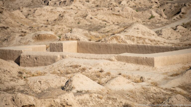 Conserved mud-brick wall foundations outlining a rectangular room plan at Ancient Panjakent, with smooth, stabilized earthen surfaces.