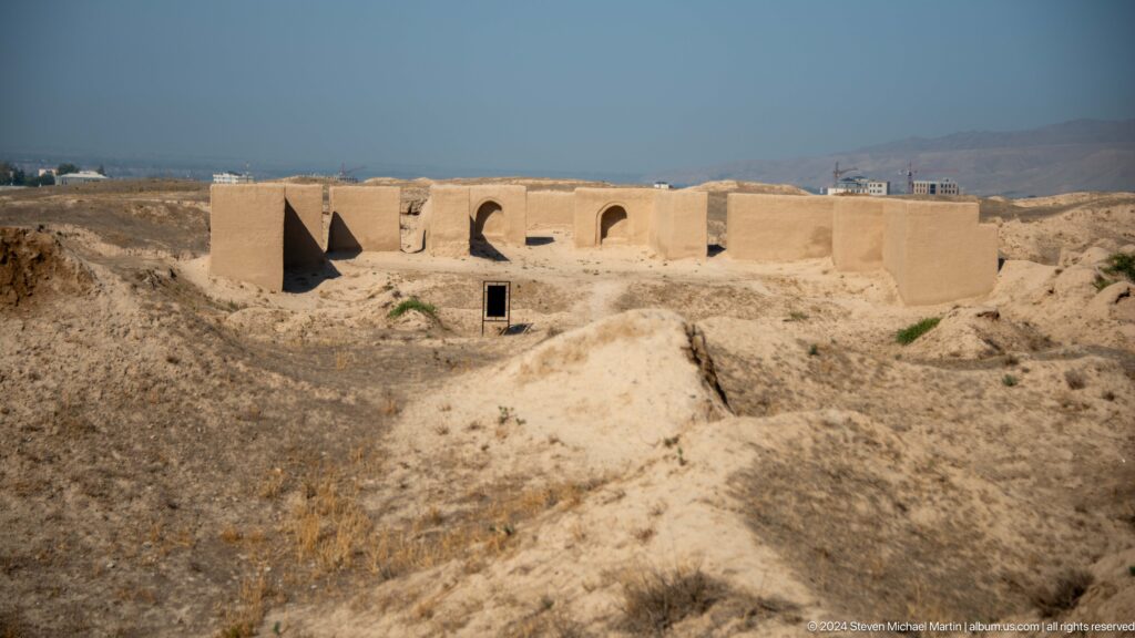 Elevated view of a reconstructed earthen building at Ancient Panjakent with multiple arched openings and stabilized mud-brick walls.