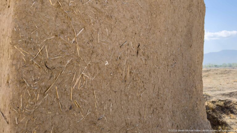 Close view of a straw-reinforced earthen wall surface at Ancient Panjakent, showing visible straw fibers embedded in cracked mud plaster.