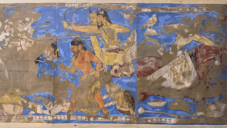 Close view of a damaged Sogdian narrative mural from Ancient Panjakent, showing a male figure and animals against a vivid blue background on fragmentary plaster.
