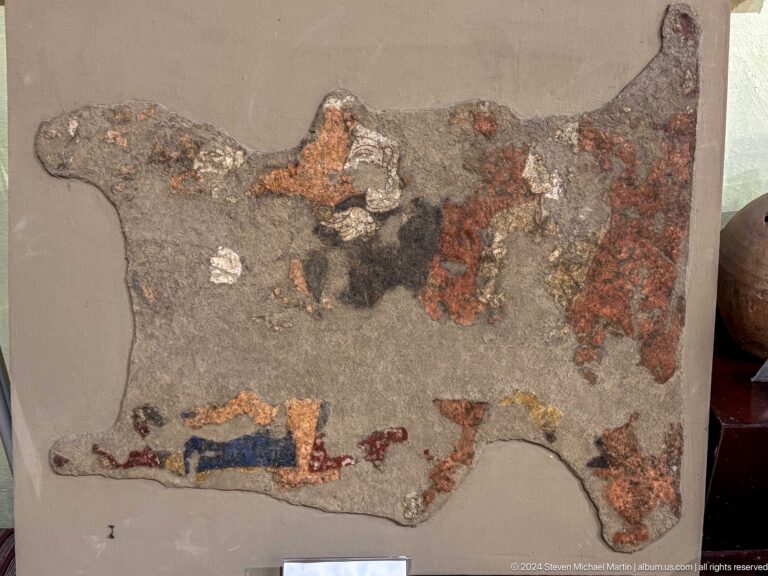 Highly damaged fragment of a Sogdian figural wall painting from Ancient Panjakent, preserving scattered painted forms on irregular plaster with major surface losses.