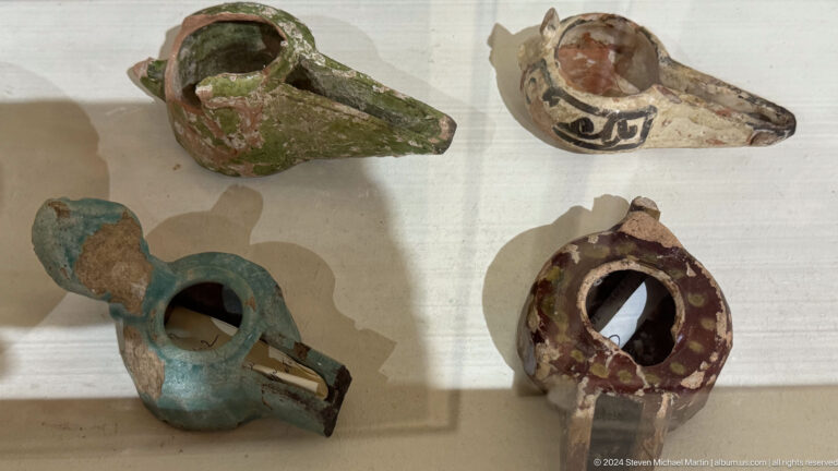 Museum display case with four small painted ceramic vessels from the Panjakent archaeological collection.