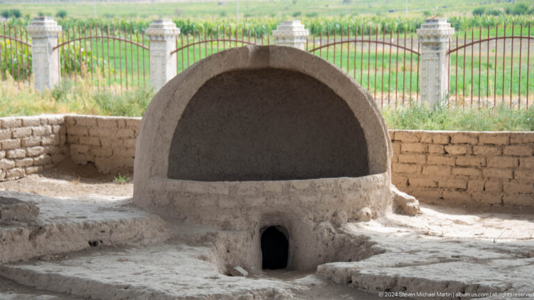 Close view of a reconstructed or conserved domed earthen oven or hearth with a small rectangular fire opening at its base.