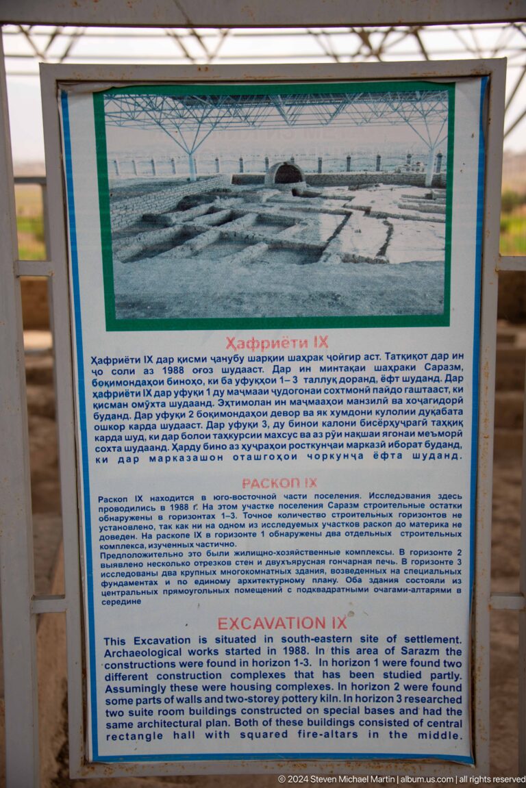 Blue-bordered information panel under a shelter at Sarazm, with Tajik, Russian, and English text and a small diagram near the top.