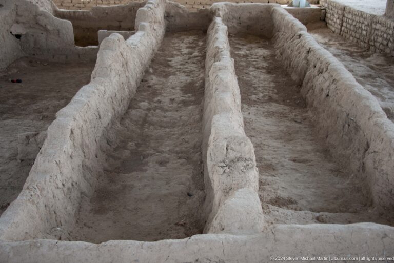 Two long, narrow excavated channels at Sarazm, bordered by conserved mud-brick earthen walls.