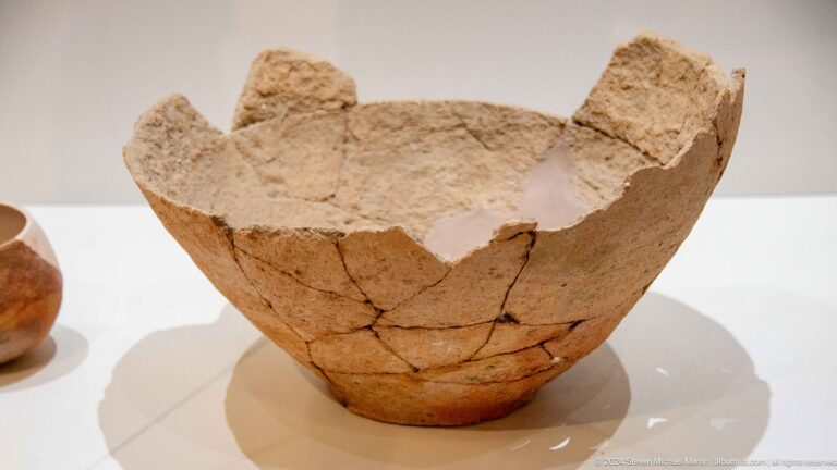 Reconstructed tan ceramic bowl from Sarazm with a broad open form and visible cracks and restored joins.