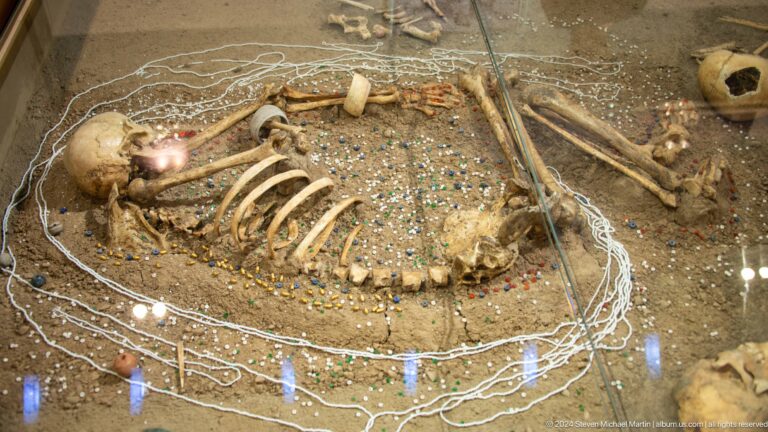 Excavated flexed human skeleton in a burial pit at Sarazm, with small objects around the bones.