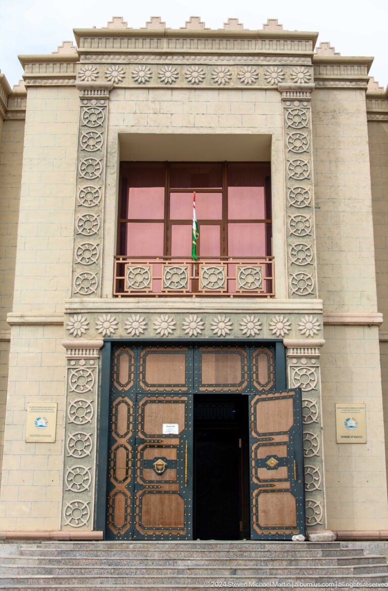 Ornamental entrance facade of the Sarazm museum with balcony, carved or patterned bands, and central double doors framed by colored panels.