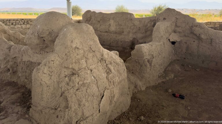 Eroded mud-brick wall remains at Ancient Sarazm with heavily cracked surfaces and visible openings and recesses.