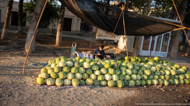 Roadside watermelon stall beneath a simple canopy.