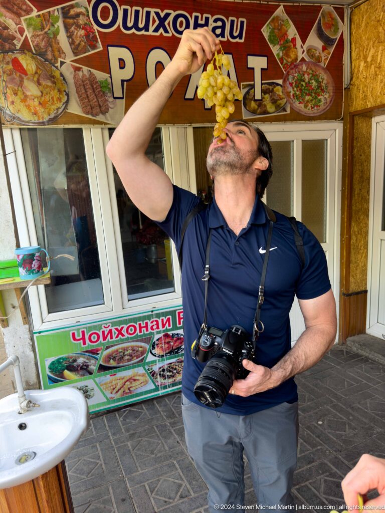 Male traveler tasting grapes outdoors.