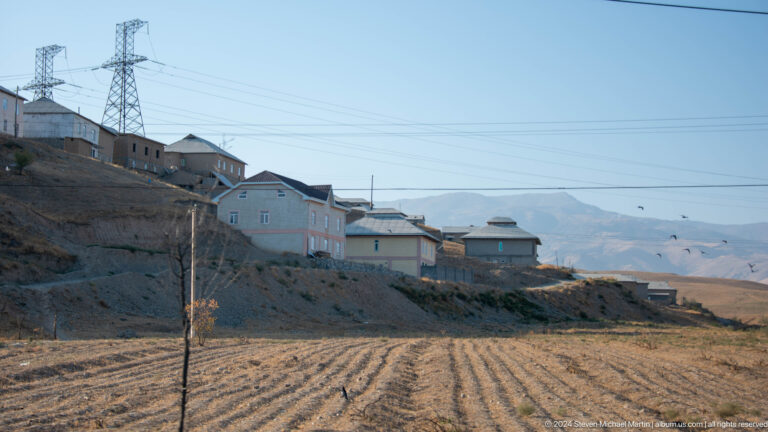 Tilled earth and modest houses at the edge of town.