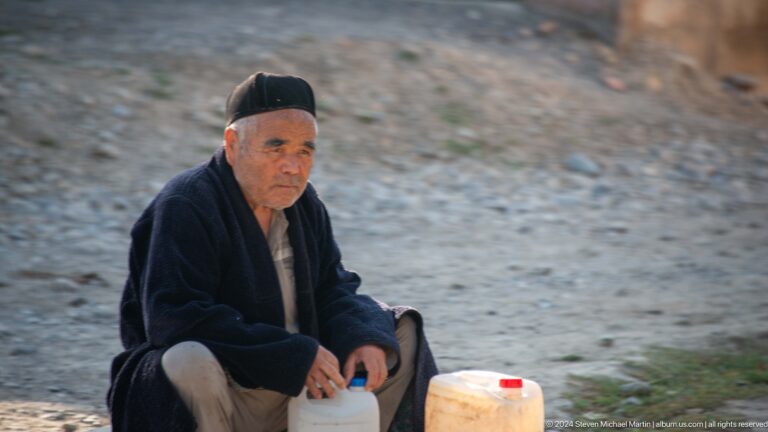Seated elderly man wearing a black cap.