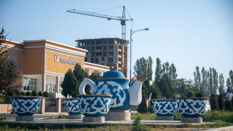 Large blue-and-white ceramic teapot sculpture in a traffic circle.