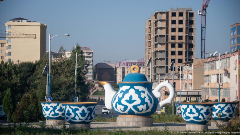 Blue-and-white teapot monument framed by city buildings.
