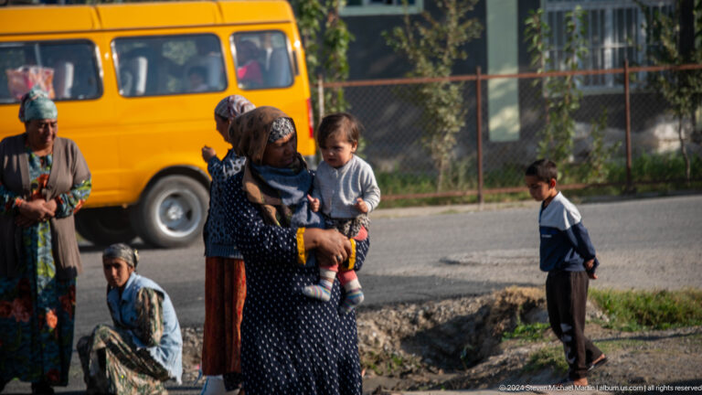 Woman holding a child beside a yellow bus.