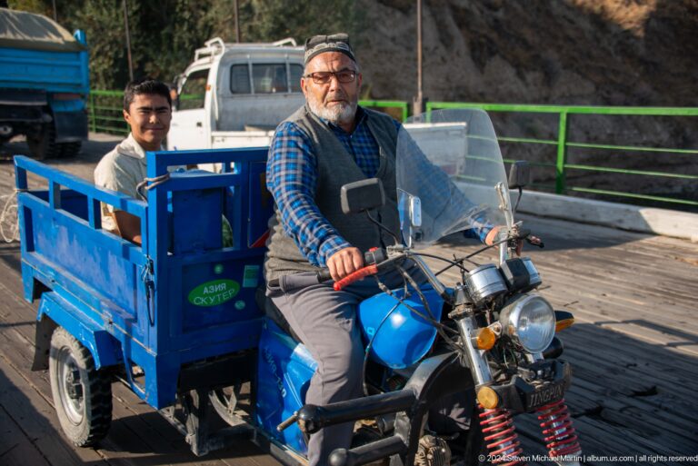 Man driving a blue three-wheeled cargo motorcycle.