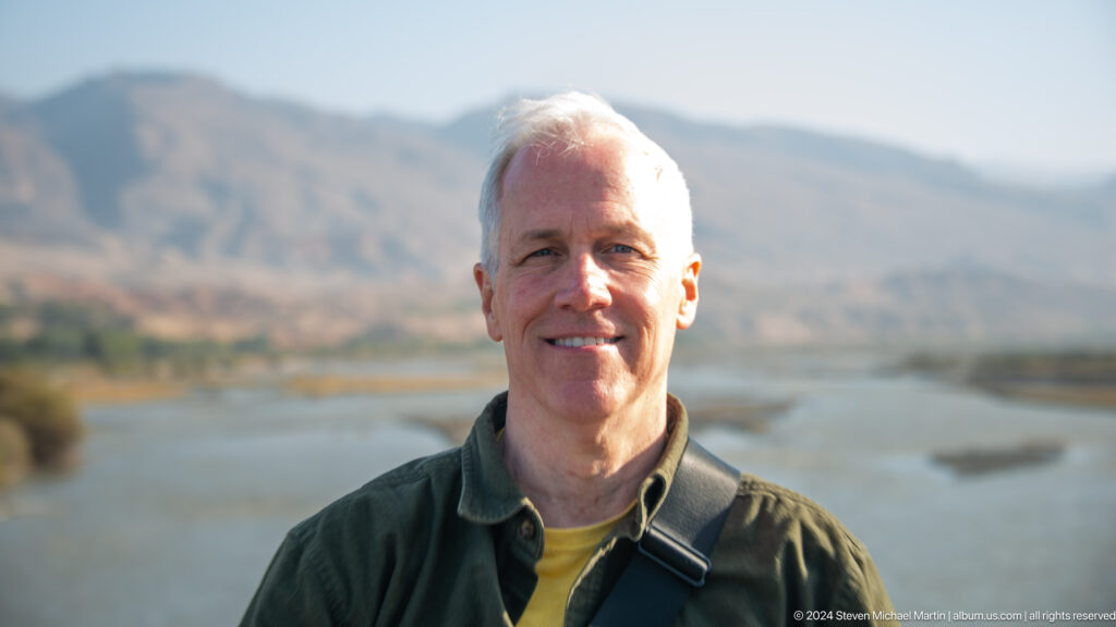 Smiling male traveler with mountains behind.