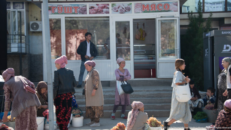 People seated outside a neighborhood shop.