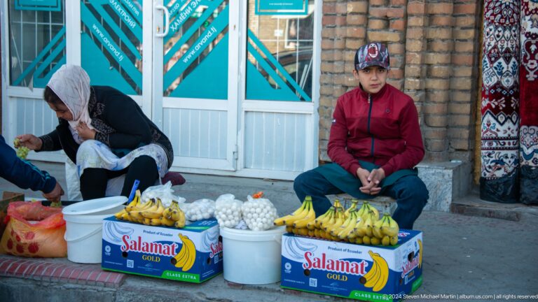 Woman selling pale round dairy products from boxes.