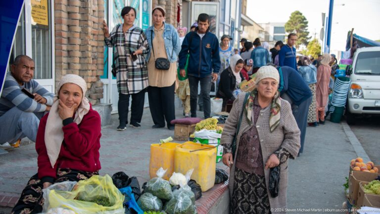 Elderly women carrying containers through a crowded market.